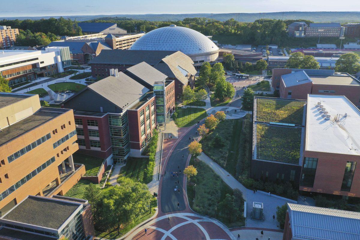 An aerial view of Fairfield Way, a pedestrian thoroughfare in the middle of UConn's Storrs campus, with the dome of Gampel Pavilion and other campus center buildings in sight