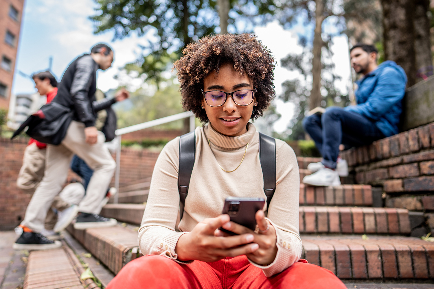 Young university student using mobile phone on stairs outdoors